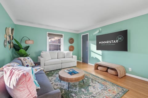 Modern living room with mint green walls, light gray couch, and wall-mounted TV.