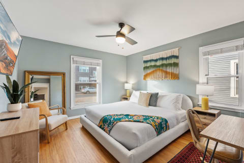 A modern bedroom featuring a large bed, colorful throw blanket, and decorative elements.