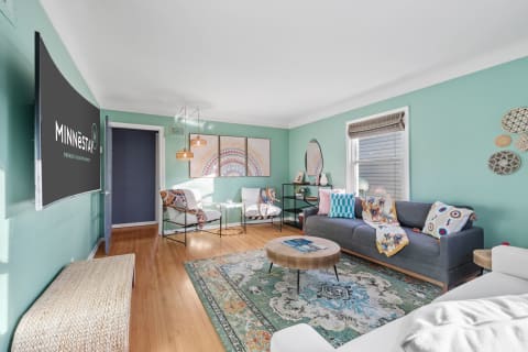 Cozy living room with teal walls, a gray sofa, and colorful decor.