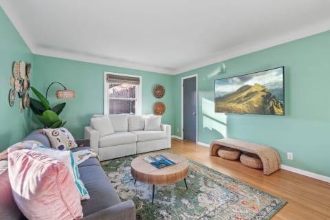 A cozy living room with mint green walls, gray and white sofas, and a wooden coffee table.