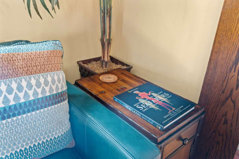 Cozy room corner with blue couch, patterned pillow, wooden table, and a book about ancient seafarers.
