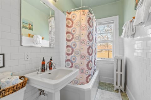 A charming bathroom with a clawfoot tub, decorative shower curtain, and neatly arranged towels.