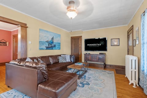 Cozy living room with leather sofa, large TV, and sailing artwork on the wall.
