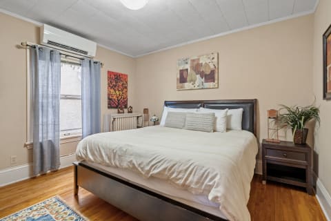 A serene bedroom with a queen-sized bed, warm wood floors, and decorative touches.