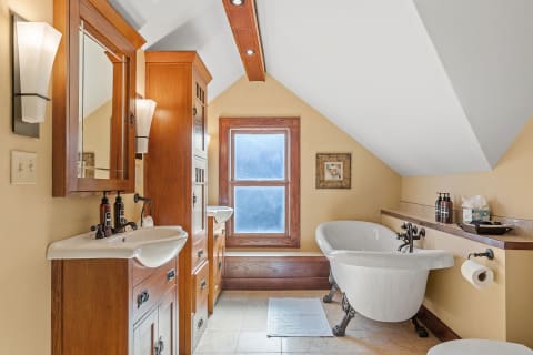 Stylish bathroom with a clawfoot tub, dual sinks, and wooden fixtures.