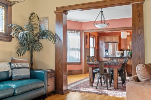 Cozy open-concept living area featuring a teal couch, wooden dining table, and modern kitchen.