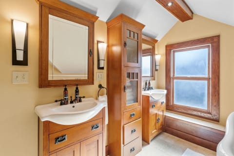 A bathroom with wooden cabinetry, a sink, and natural light from a window.