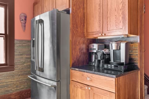 A modern kitchen with a stainless steel fridge, coffee maker, and artistic wall decor.