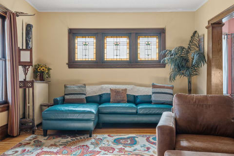 Living room featuring a teal sectional couch, decorative pillows, and stained glass windows.