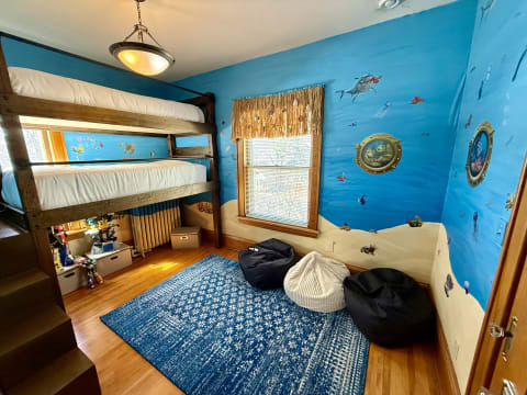 Children's bedroom featuring a bunk bed, bean bags, and ocean-themed wall art.