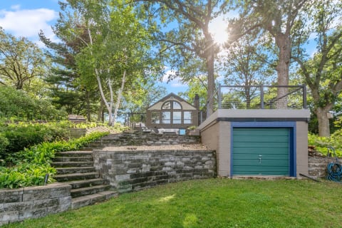 Stone steps leading to a modern structure in a lush outdoor setting.