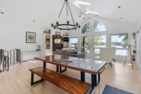 Inviting living room with a large dining table, comfortable seating, and views of a lake.