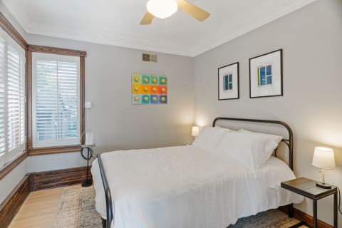 Bedroom featuring a wrought iron bed, a colorful artwork, and wooden window shutters.