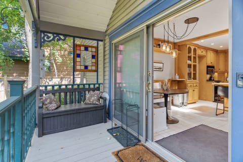 Cozy porch area with a bench and a stained glass window leading to a kitchen.