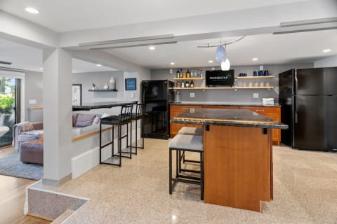 Contemporary kitchen with granite countertop, black stools, and ample shelving.