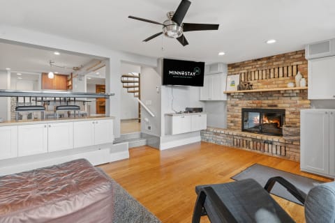 Modern living room with a fireplace and a television, featuring wooden flooring and a spiral staircase.