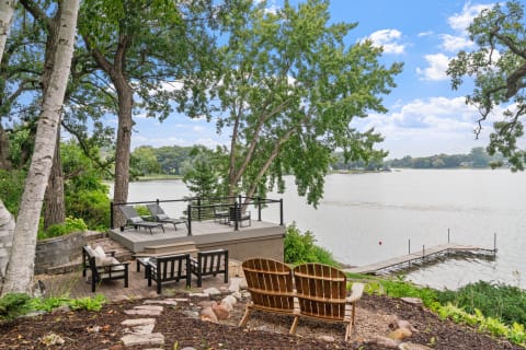 A serene lakeside scene with deck chairs and a dock overlooking the calm water.