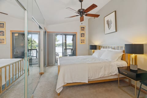 Stylish bedroom with a view of a lake through sliding glass doors.