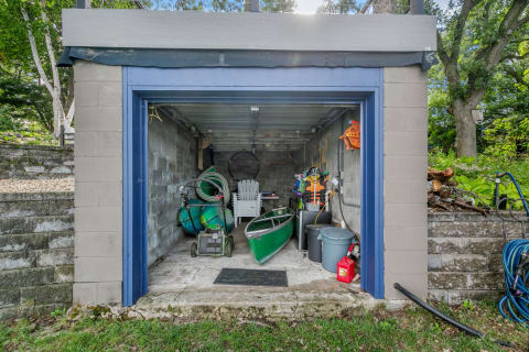 A small storage shed containing various outdoor equipment including a canoe and lawnmower.