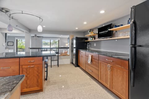 Contemporary kitchen featuring wooden cabinets, granite countertops, and natural light from windows.