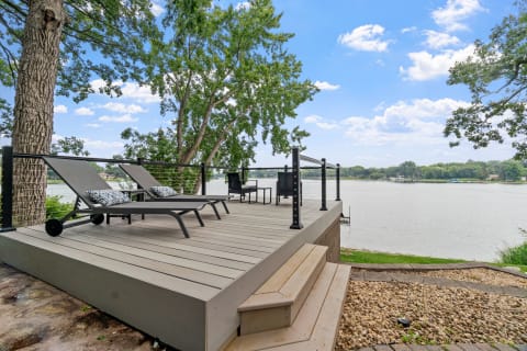 Deck with lounge chairs by a lake under a blue sky