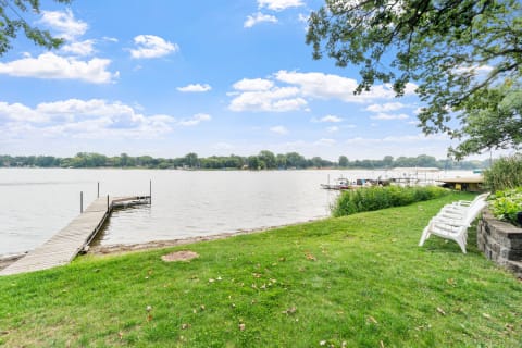 Lakeside view featuring grass, a wooden dock, and boats.