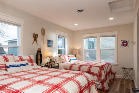 A well-decorated bedroom featuring plaid beds, wooden decor, and natural light.