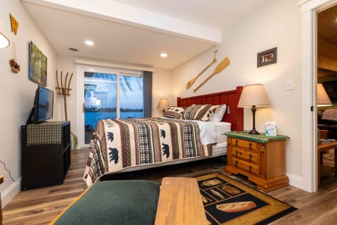 Cozy bedroom featuring a bed with a bear motif quilt, a view of a lake, and rustic decor elements.