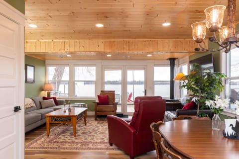 Lakeside living room featuring wood beams, cozy furniture, and large windows overlooking the lake.