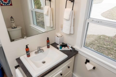 Modern bathroom sink with toiletries and towels, featuring a nautical lighthouse decoration.