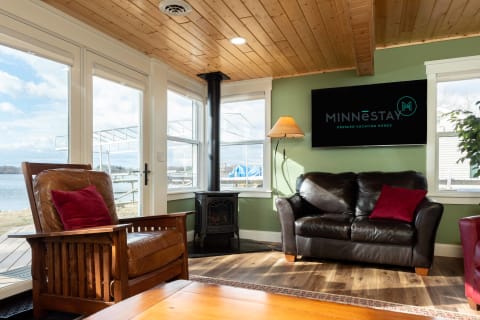 A cozy living room with lake views, featuring leather seating and a traditional wood stove.