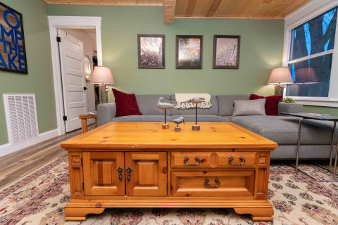 A cozy living room with a wooden coffee table, gray sectional couch, and decorative birds.