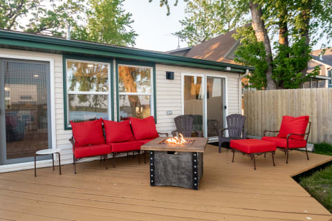 Outdoor patio with red cushioned seating and fire pit, surrounded by a peaceful landscape.