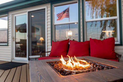A lakeside retreat with a fire table, red cushions, and clear windows showing an American flag.
