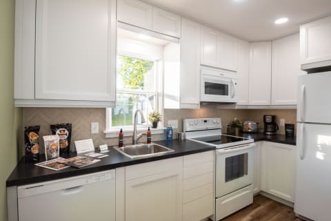 A well-equipped modern kitchen featuring white cabinets, black countertops, and stainless steel appliances.