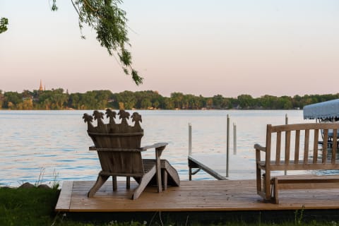 Serene lakeside view with a wooden throne-like chair and bench during sunrise.