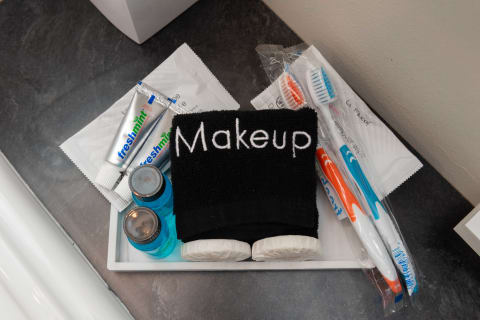 A collection of personal care items on a countertop, featuring a black towel labeled 'Makeup', toothpaste, toothbrushes, and mouthwash bottles.