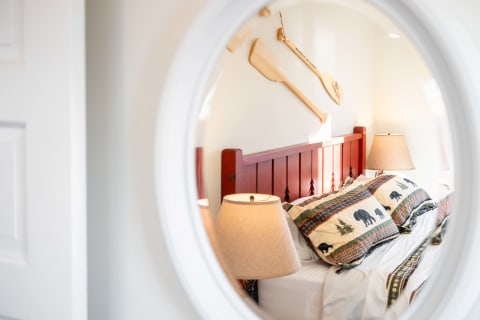 Reflection of a rustic bedroom with a red bed and bear-patterned quilt.