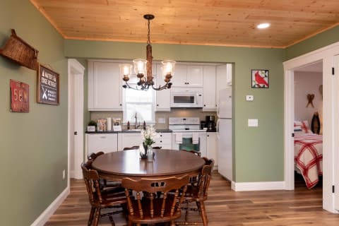 A cozy dining space featuring a wooden table with chairs and a vintage-style chandelier, adjacent to a modern kitchen.