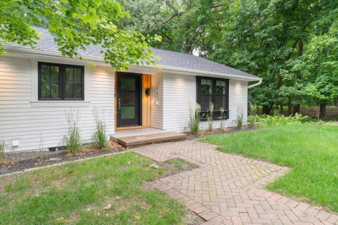 Front view of a modern house with a pathway and greenery around it.