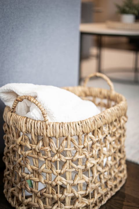 Woven basket with a white blanket inside, set against a blurred modern background.