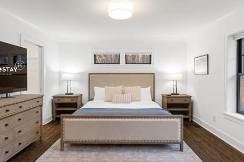 Modern bedroom featuring a king-size bed, wooden furniture, and warm lighting.