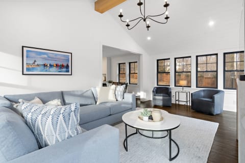 Bright living room featuring a light blue sectional sofa, art on the wall, and large windows.