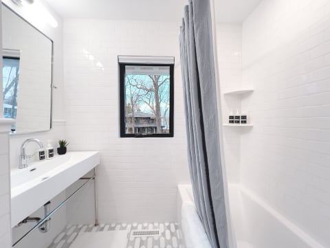 Modern bathroom with white subway tiles, a sleek sink, and a view of trees outside.