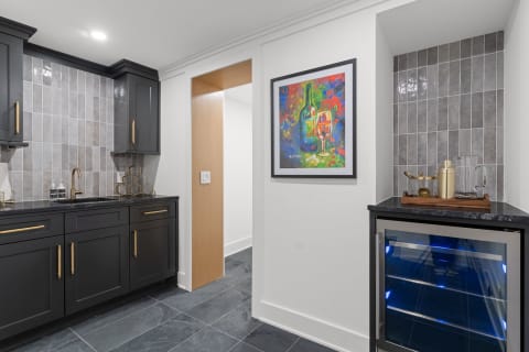 Contemporary kitchen featuring black cabinets, a colorful painting, and a wine cooler.