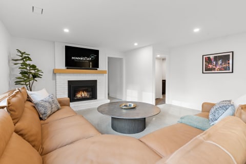 Contemporary living room featuring a leather sectional, round coffee table, and a fireplace.