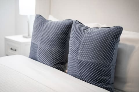 Two blue decorative pillows with a geometric design on a white bed.