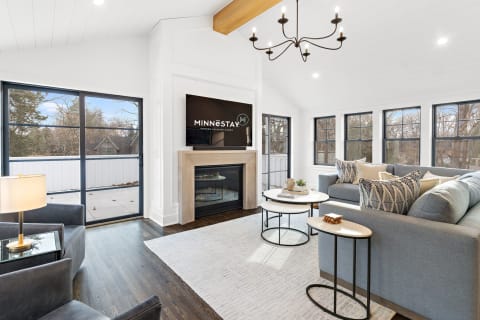 A contemporary living room featuring a gray sectional sofa, coffee tables, and a flat-screen TV above a modern fireplace.