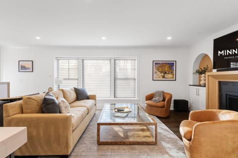 Cozy and stylish modern living room featuring a beige sofa, glass coffee table, and colorful artwork.