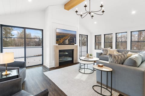 Contemporary living room with gray sectional sofa, fireplace, and large windows.